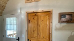 Een kamer met een houten deur, een klein raam met gordijnen en een aan de muur bevestigde Amerikaanse vlag.