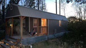 Een klein, gelijkvloers huisje met een veranda en een overdekt zitgedeelte buiten.