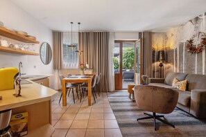 A modern living room with a sofa, a dining table, and a kitchen area with shelves. - Apartment 'Mair In Schenna C' with Shared Terrace and Wi-Fi (Schenna)
