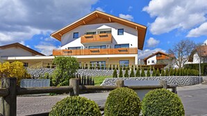 Een modern huis met twee verdiepingen, een gevel van natuursteen, houten balkons en een verharde oprit.