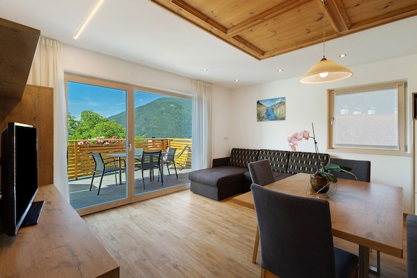 Un interior moderno con techo de madera, un sofá, una mesa de comedor y un televisor.