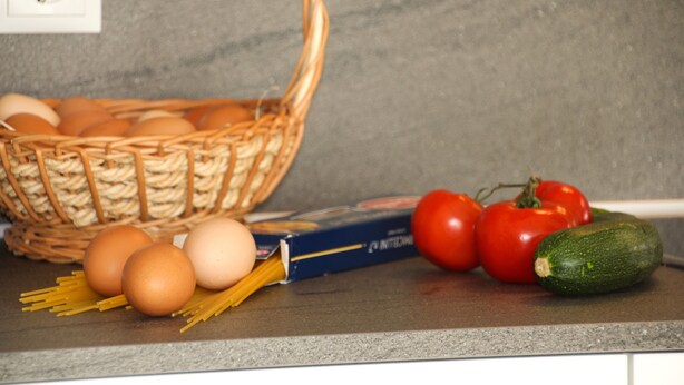 A kitchen counter with a basket of eggs, tomatoes, a zucchini, and a box of pasta. - Holiday Apartment 'Edelweiß' with Mountain View, Shared Garden and Wi-Fi (Rasa)