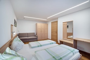 Une chambre avec deux lits, un canapé, une armoire et un miroir.