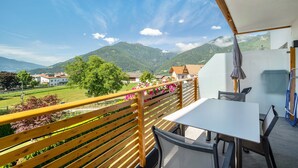 A balcony with a table and chairs, overlooking a mountainous landscape with houses in the background. - Holiday Apartment 'Edelweiß' with Mountain View, Shared Garden and Wi-Fi (Rasa)