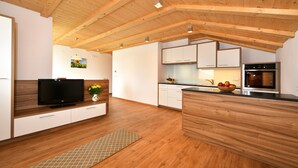 A modern kitchen with wooden beams, white cabinets, a built-in oven, and a television on a wooden console. - Apartment 'Sonnenblume' with Mountain View, Shared Garden and Wi-Fi (Rasa)
