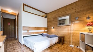 Un dormitorio con cabecera de madera, una mesita de noche, una lámpara y un espejo en la pared.