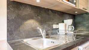 Una cocina con encimera de granito, pileta de acero inoxidable y escurreplatos.