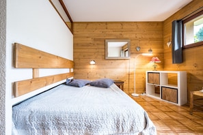 A wooden-paneled room with a bed, bedside lamp, and a small cabinet.
