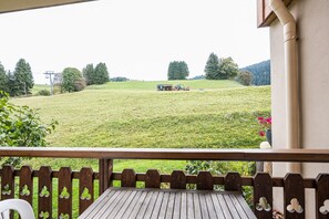 A wooden deck with a view of a green field and a tractor.