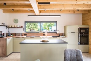 Una cucina moderna con travi in legno, un'ampia finestra ed elettrodomestici integrati.