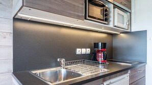 Een moderne keuken met een roestvrijstalen spoelbak, een afwassysteem, een magnetron en een koffieapparaat.