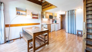 Een keuken met houten kastjes, een eettafel en een inbouwmagnetron.