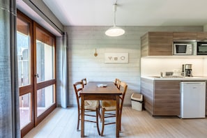 Une cuisine moderne avec des meubles en bois, un four à micro-ondes encastré et un coin repas comprenant une table et des chaises en bois.