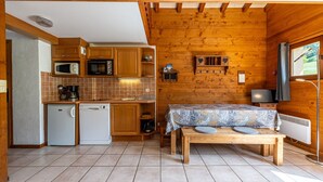 A compact kitchen with wooden cabinets, a microwave, a coffee maker, and a small refrigerator. - Apartment 'Le Lachat' with Mountain View, Shared Terrace and Wi-Fi (Cohennoz)