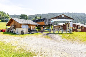 A building with a wooden facade, a covered area with a roof, and a sign indicating a location.