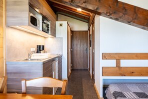 A compact kitchen with a microwave, sink, and wooden cabinets.
