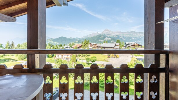 Ein Holzbalkon mit Blick auf Berge und ein Dorf.