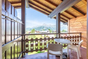Ein Holzbalkon mit Tisch und Stühlen, mit Blick auf eine Berglandschaft.