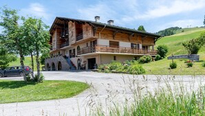 Ein großes Holzgebäude mit Balkon, steinernen Eingang und einem Schild mit der Aufschrift 'La Croix des Amadis'.