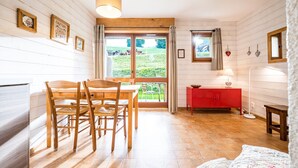 Una habitación con una mesa de comedor de madera, sillas, un armario rojo y vistas a un campo verde a través de un ventanal grande.