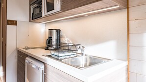 Una cocina moderna con microondas integrado, pileta de acero inoxidable y escurreplatos.