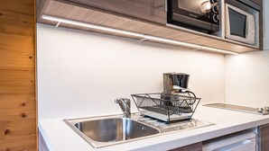 A kitchen with a stainless steel sink, a dish rack, a microwave, and a dishwasher. - Studio Apartment '2 - L'Edelweiss' with Mountain View, Shared Garden and Wi-Fi (Cohennoz)