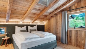 Quarto de madeira com cama, janela e vista para vegetação.