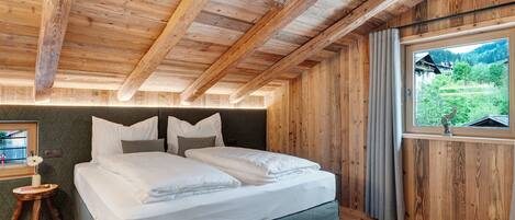 A wooden room with a bed, window, and a view of greenery.