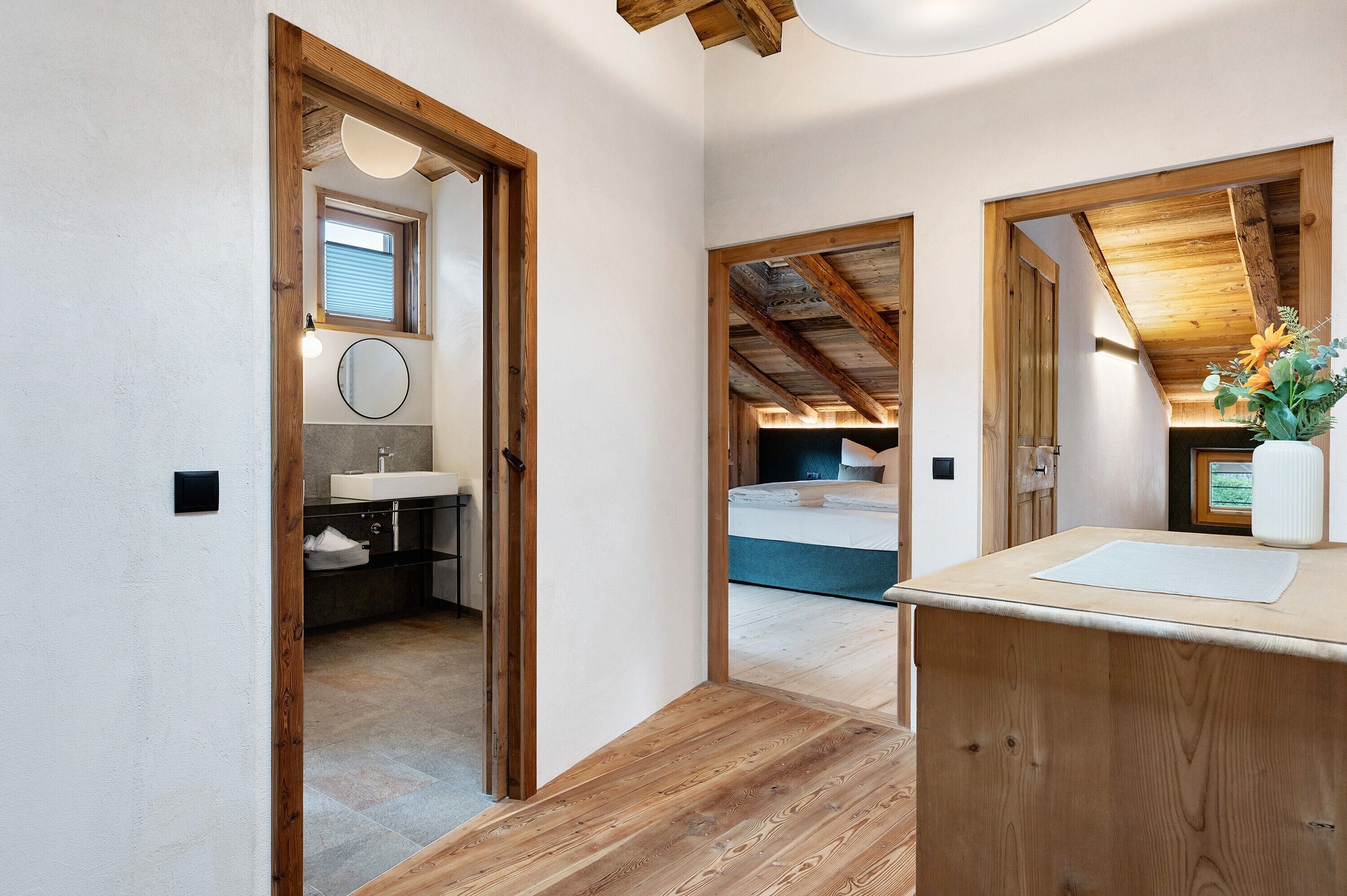 A bedroom with a bed, a wooden ceiling, and a window.