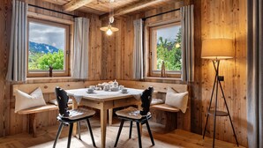 Um quarto com painéis de madeira, com uma mesa posta para o chá, duas cadeiras, um banco e um abajur.