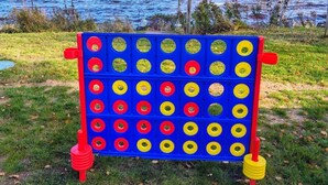 A board game setup with a grid of red and yellow circles, placed on grass near a body of water. - Studio #2 On Lake Superior, Water Views and Outdoor Adventure Await! (Paradise)