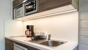 A modern kitchen with a built-in microwave, coffee maker, and stainless steel sink. - Studio Apartment '10 - Bisanne' with Mountain View, Shared Garden and Wi-Fi (Cohennoz)