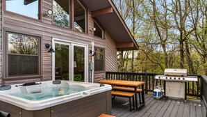 Eine Terrasse mit Whirlpool, Grill und Picknicktisch.