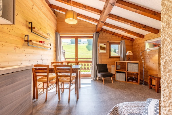 Un intérieur en bois comprenant un coin repas, un lit et un bureau avec une lampe.