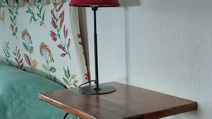 Un tavolo d'angolo con una lampada rossa, una coperta verde e un cavo di alimentazione.