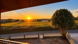 A sunset view from a covered outdoor area with a stone wall and a metal fence. - Traditional Galician Country House 'As Neveiras' with Mountain Views, Private BBQ/Garden, Wi-Fi (FIXO -FORCAREY-)