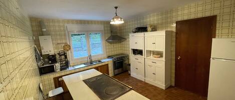 A compact kitchen with a stove, sink, and white cabinets.