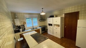 Een kleine keuken met een kookplaat, wastafel en witte kasten.