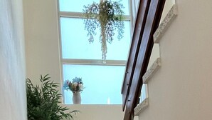 Una escalera con piso de terrazzo, una planta en maceta y una ventana con vistas.