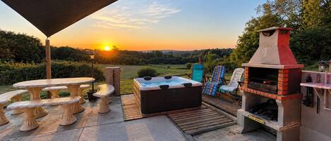 Une terrasse extérieure dotée d’un jacuzzi, d’un espace salon et d’un barbecue.
