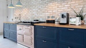 A kitchen with a brick wall, a stove, a toaster, and pendant lights.