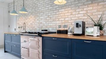 A kitchen with a brick wall, a stove, a toaster, and pendant lights.