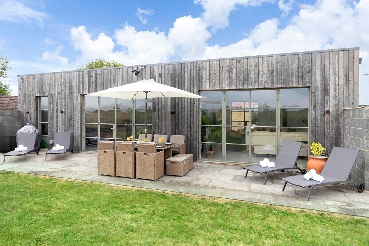 Un patio al aire libre con sillones, una mesa y una zona de parrilla.