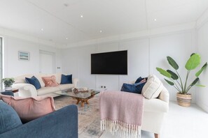A modern living room with a sofa, armchairs, a coffee table, and a large plant.