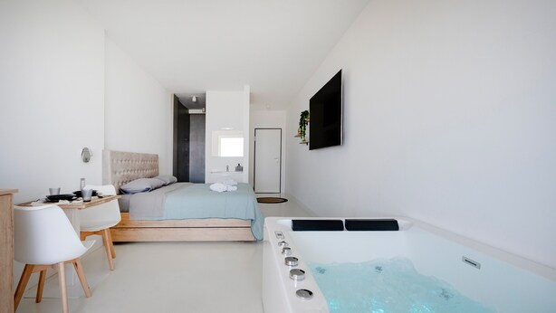 A modern bedroom with a bed, a desk, a chair, a TV, and a hot tub. - Holiday Home 'Angel Suite 2' with Balcony, Wi-Fi and Air Conditioning (Selva di Fasano)