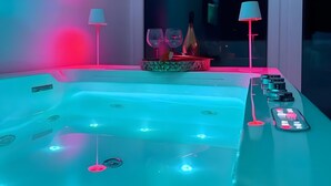 A modern bathroom with a large bathtub, two wall-mounted lamps, and a window with a view. - Holiday Home 'Angel Suite 2' with Balcony, Wi-Fi and Air Conditioning (Selva di Fasano)