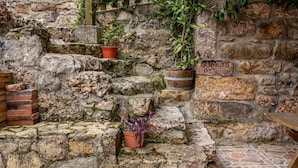 A stone wall with steps, potted plants, and a wooden bench. - Casa Rural Ricao with Mountain Views, Private Terrace and WiFi (Cangas de onis)