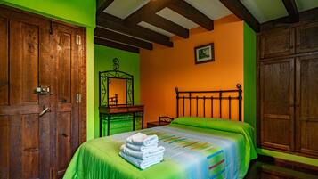 Habitació amb llit, armari de fusta i escriptori amb mirall.
