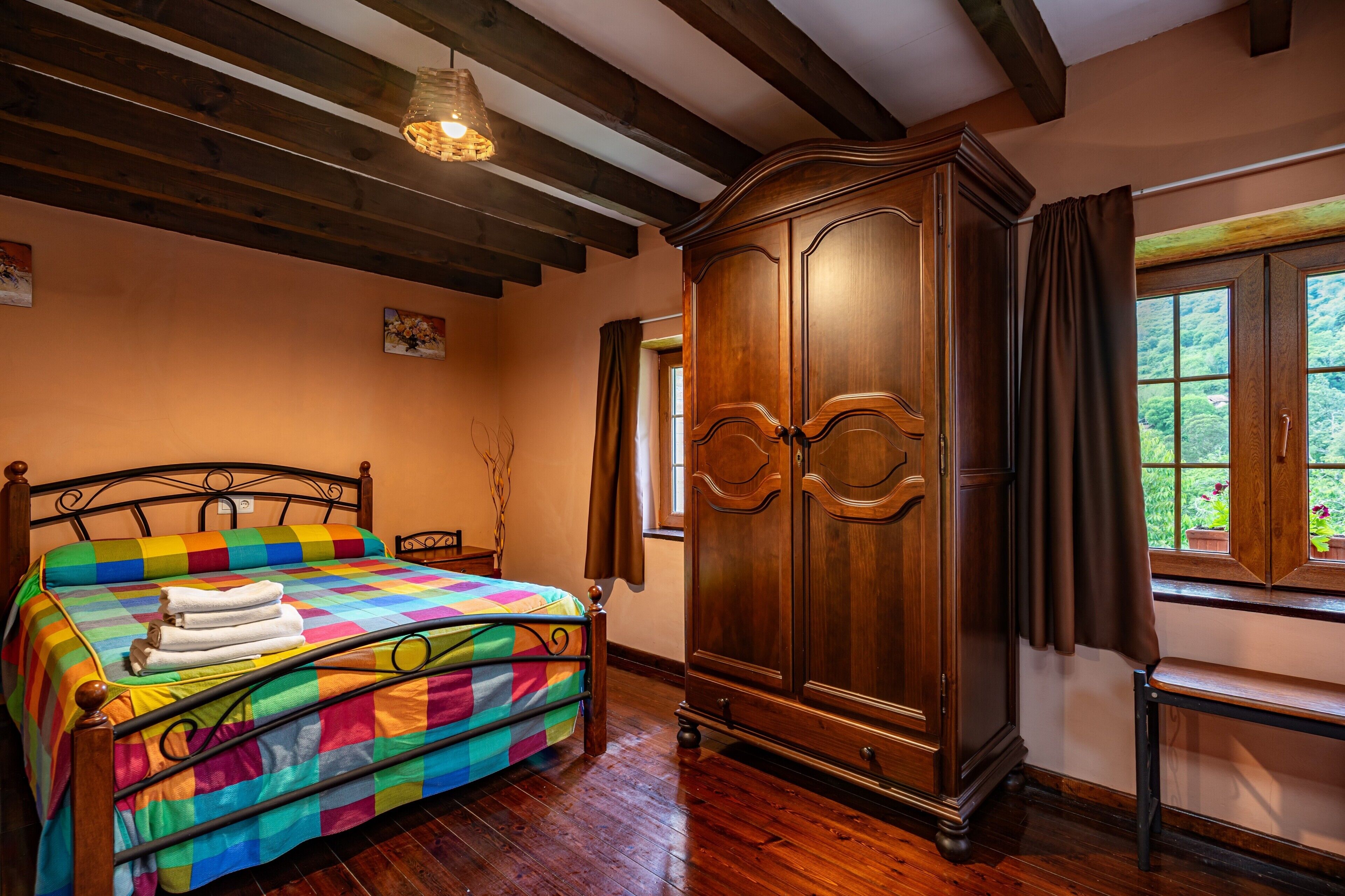 Un dormitorio con una cama de madera, un armario grande y un ventanal con vistas.