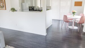 A modern kitchen with white cabinets, a dining area with pink chairs, and a large window with sheer curtains. - Soothing 2-bedroom house with WiFi in Vista (Vista)